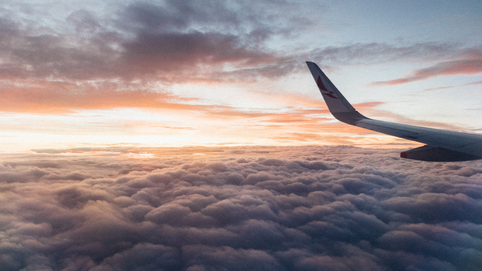 An aircraft wing above the clouds at sunset
